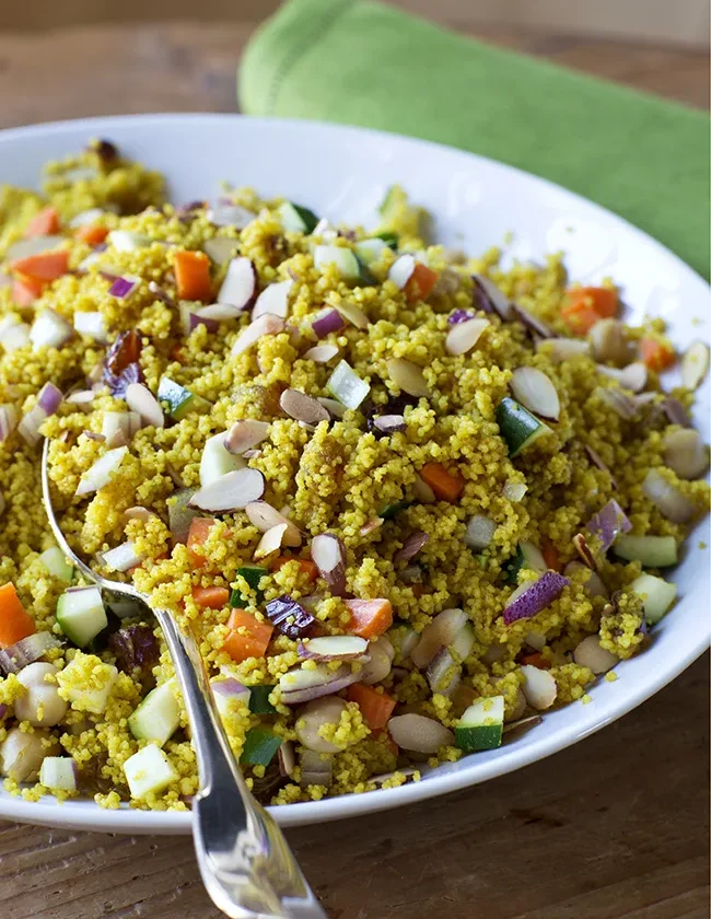 Ina Garten summer vegetable couscous with diced zucchini, carrots, red onion and toasted almonds in a white bowl