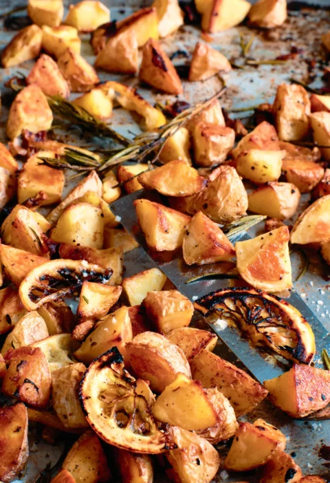 Ina Garten Tuscan roasted potatoes and lemon on a sheet pan with caramelized lemon slices and rosemary