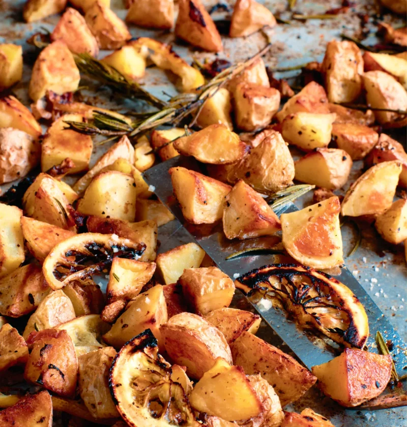 Ina Garten Tuscan roasted potatoes and lemon on a sheet pan with caramelized lemon slices and rosemary