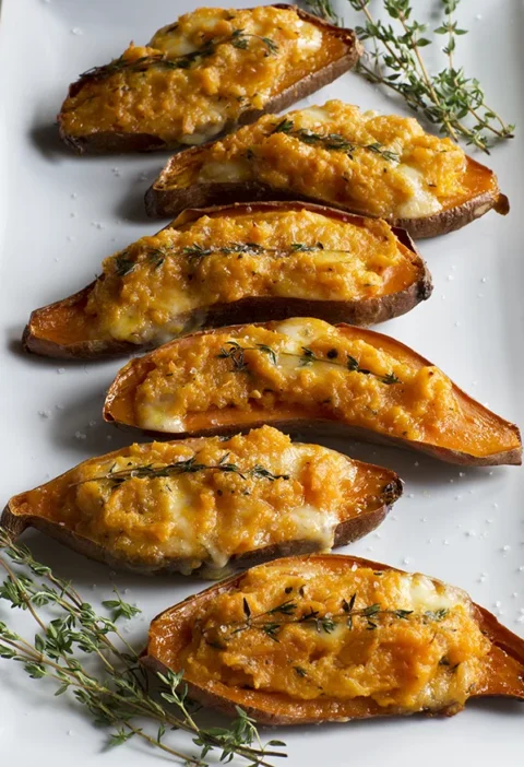 Ina Garten twice-baked sweet potatoes topped with melted Taleggio and fresh thyme sprigs on a white platter